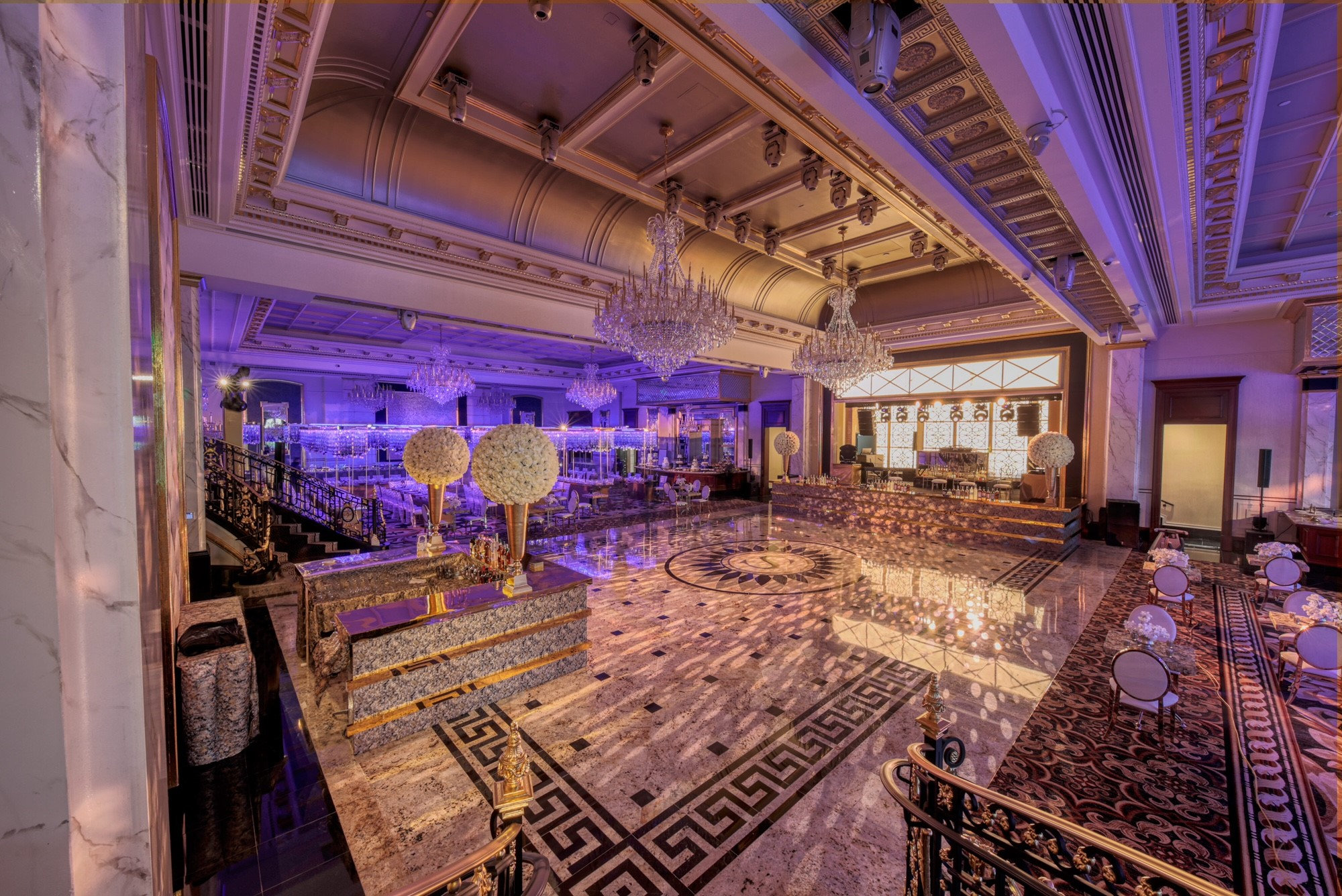 The ballroom lit in violet with a monogrammed dance floor