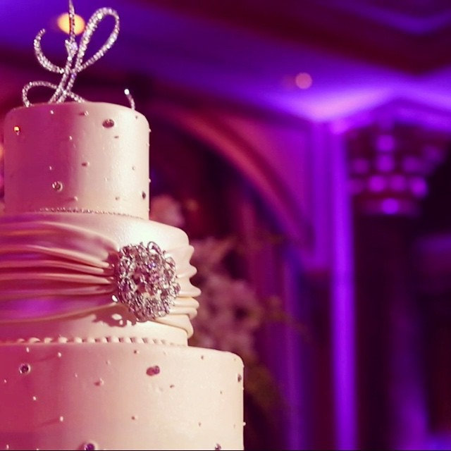 A pink-lit wedding cake with jewelled brooch