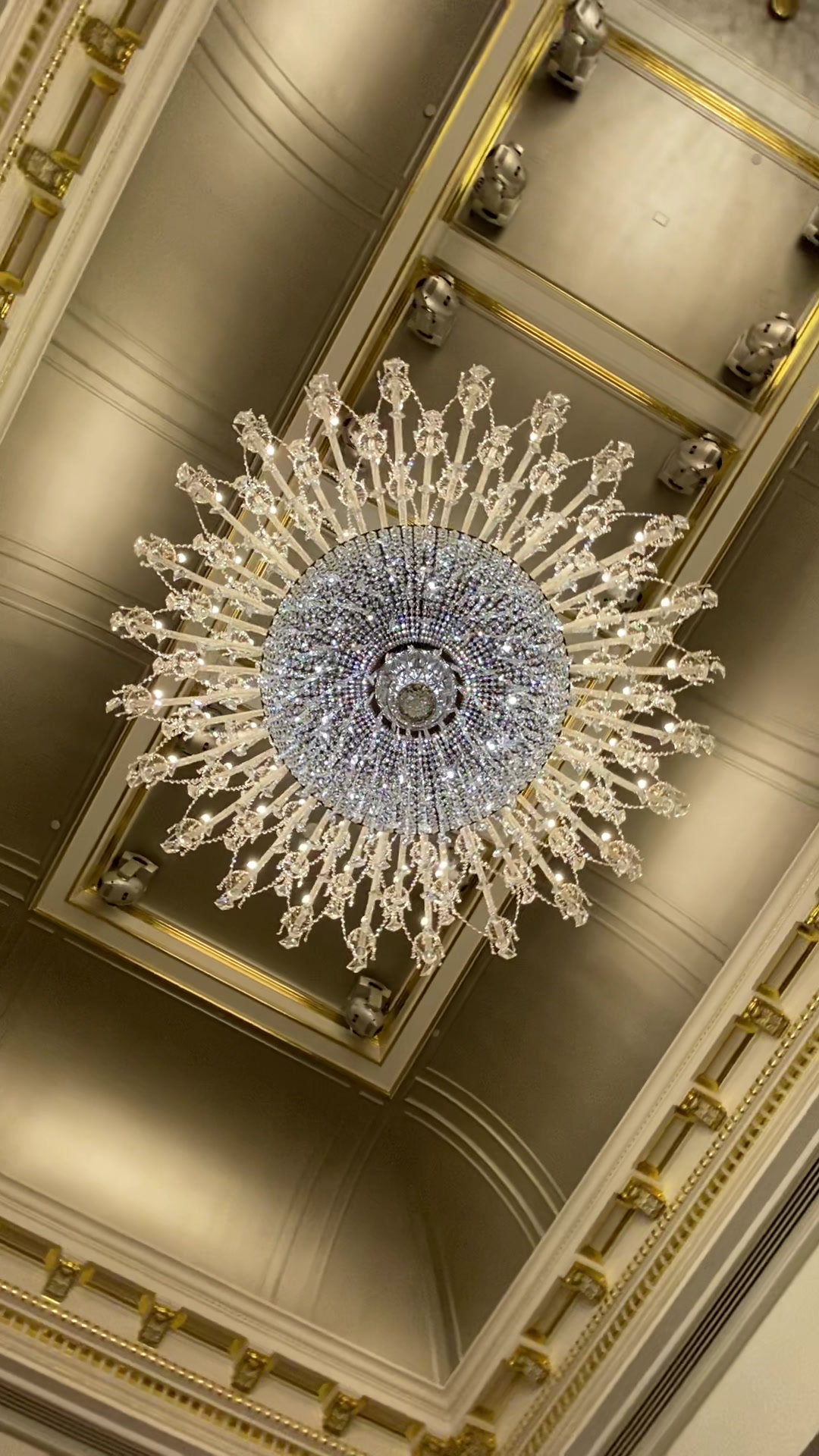 A crystal chandelier seen from below, set in a gilded coffer