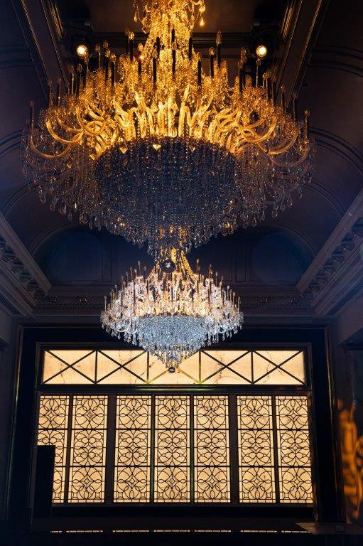 Tiered golden chandeliers above a lattice window
