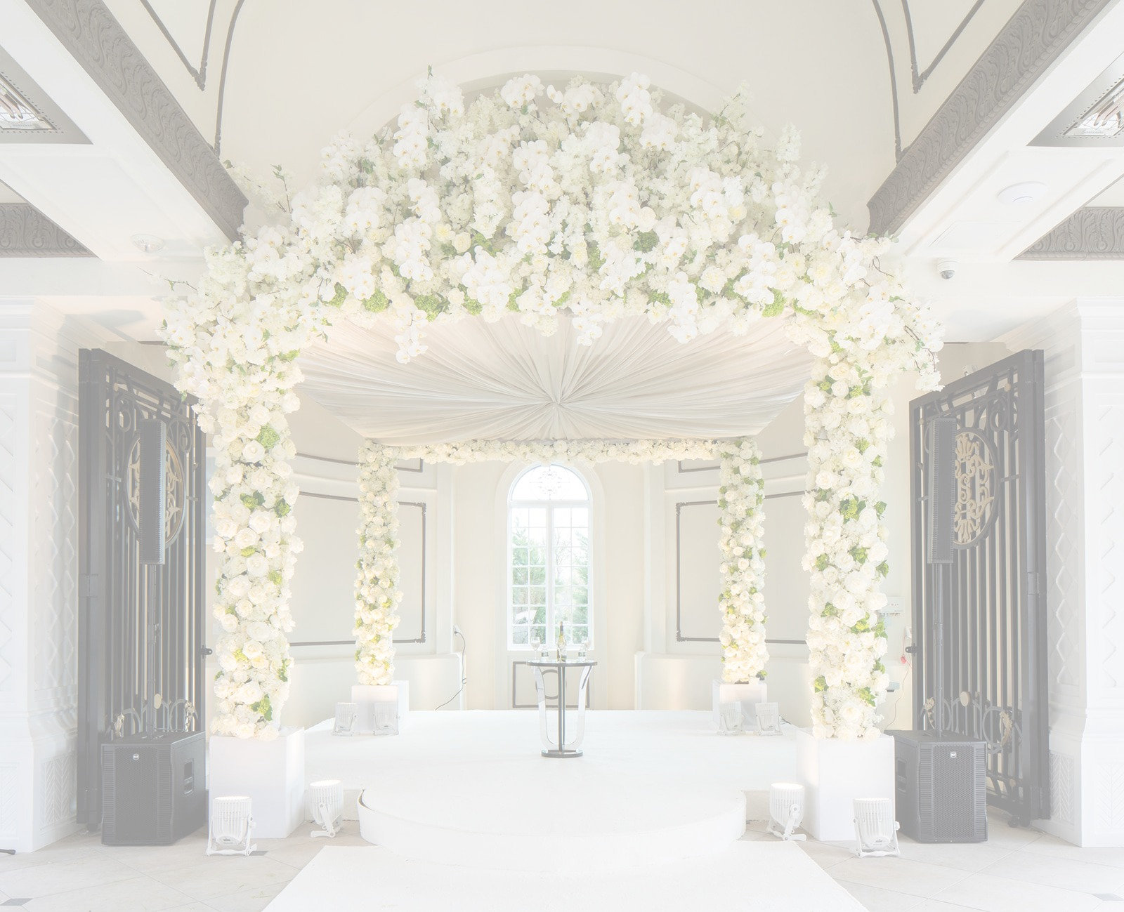 A chuppah of white florals in a sunlit hall