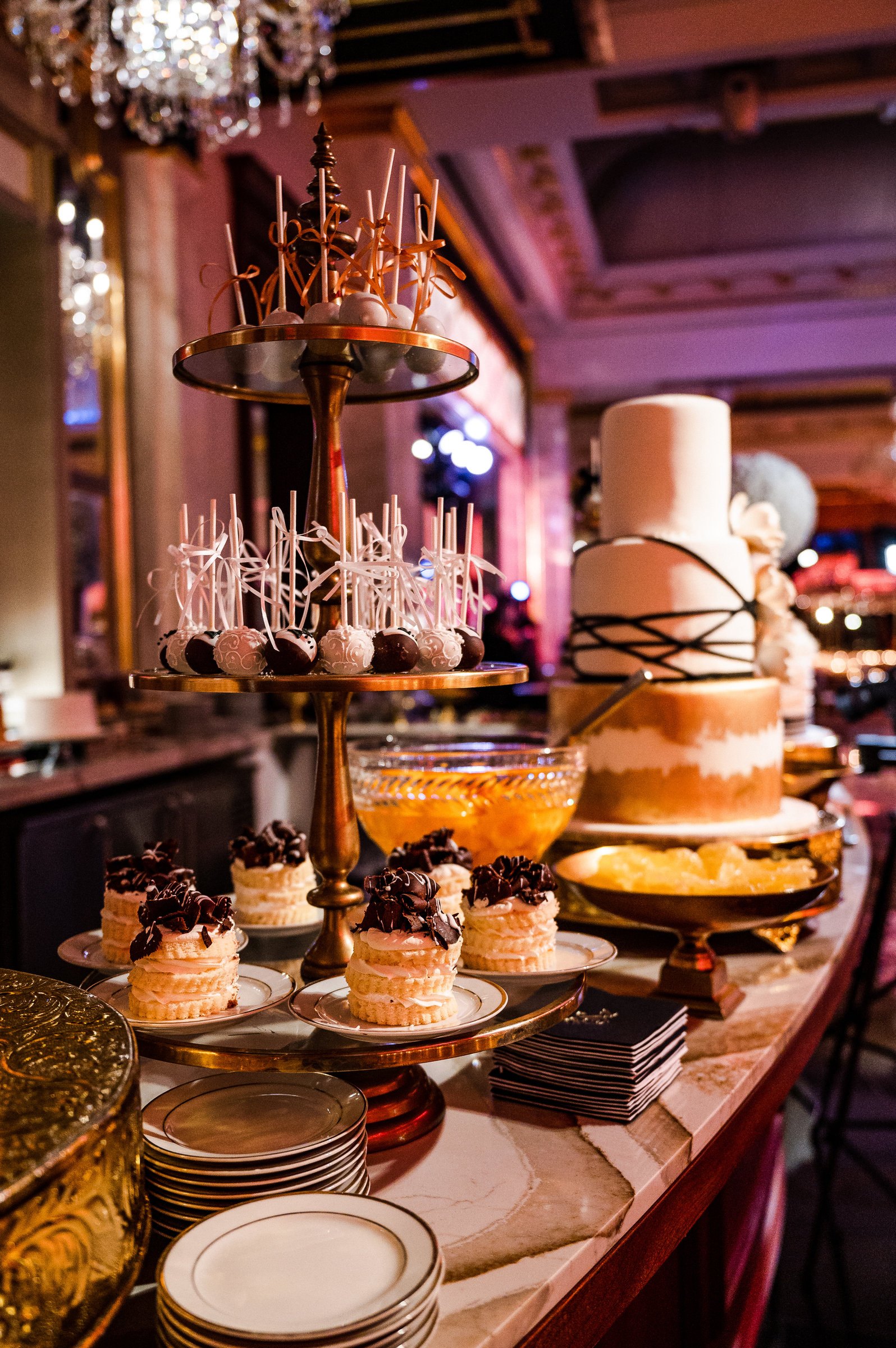 A tiered cake and dessert display in warm light