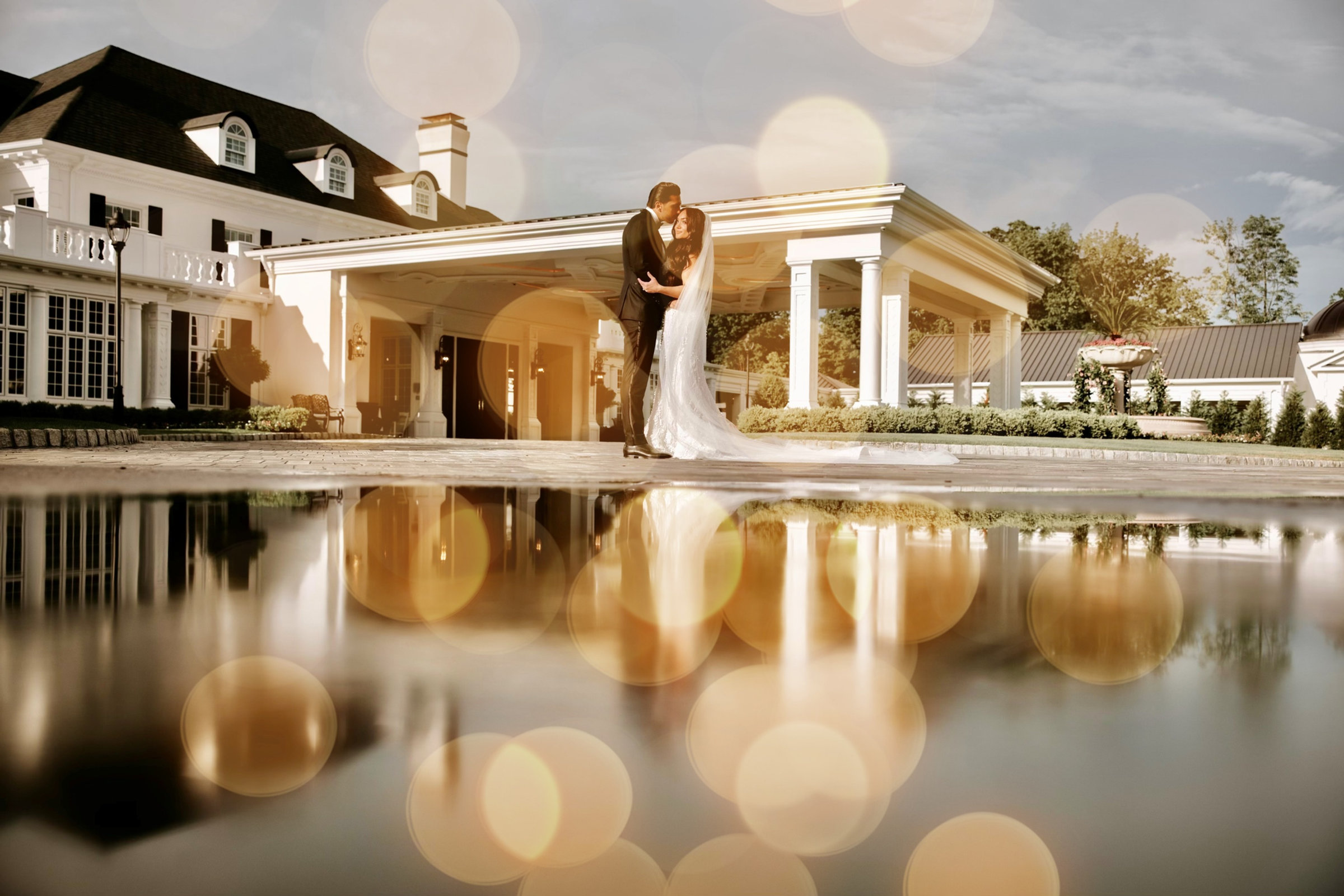 A couple reflected in the pool before the white Georgian mansion at dusk