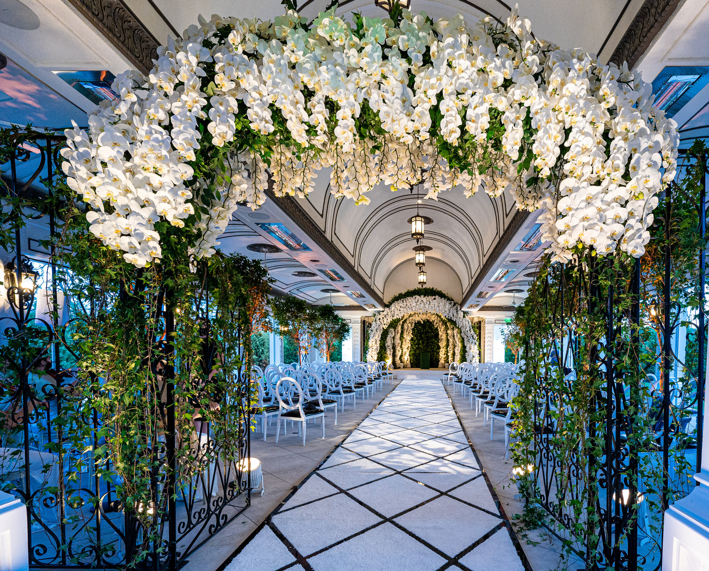 An aisle under an arch of white orchids