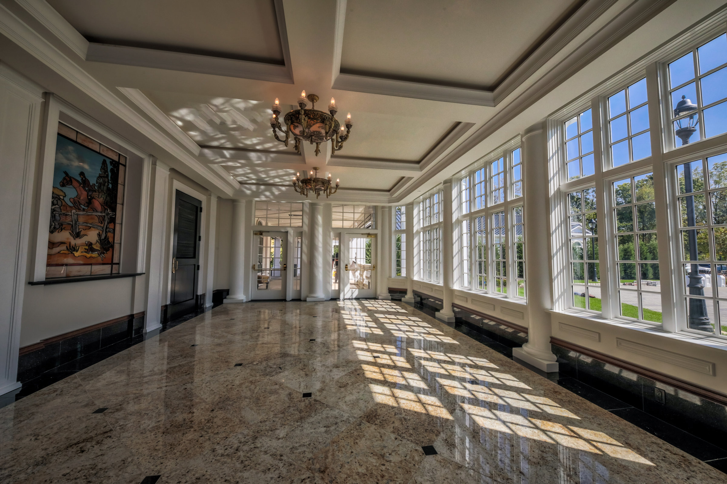 A sunlit gallery of tall windows and marble floors